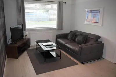 a living room with a leather couch and a television at 3 Bedroom-Kelpies Serviced Apartments Burns in Falkirk