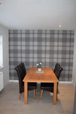 a dining room table with chairs and a vase of flowers at 3 Bedroom-Kelpies Serviced Apartments Burns in Falkirk