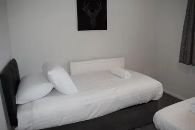 a white bed with two pillows in a bedroom at 3 Bedroom-Kelpies Serviced Apartments Burns in Falkirk