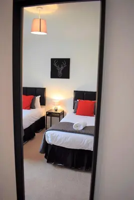 a mirror reflection of a bedroom with two beds at Kelpies Serviced Apartments MacGregor- 2 Bedrooms in Grangemouth