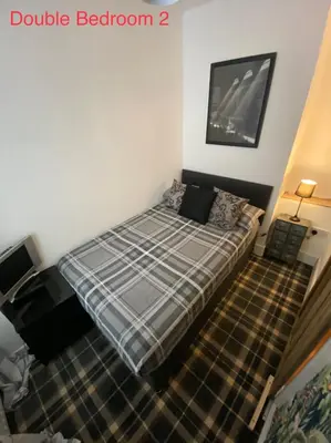 a bedroom with a bed with a plaid blanket at Glasgow City Centre Apartment in Glasgow
