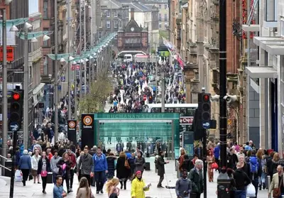 a crowd of people walking down a busy city street at Glasgow City Centre Apartment in Glasgow
