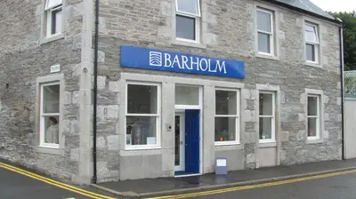 a brick building with a blue sign on it at Barholm Accommodation in Creetown