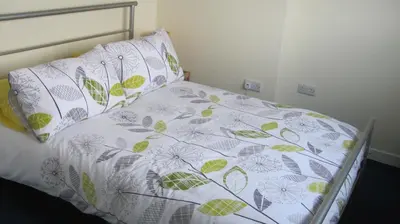 a bed with green and white sheets and pillows at Barholm Accommodation in Creetown