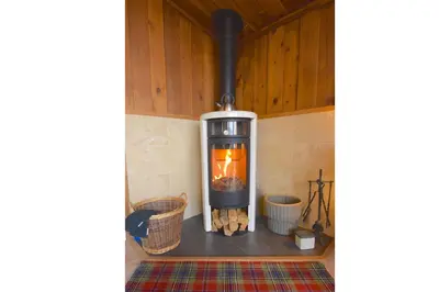 a wood burning stove in a room with baskets at Dalriada by Loch Goil in Carrick