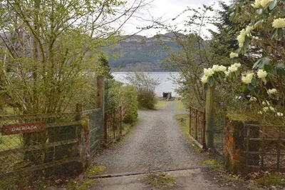 a path with a fence next to a body of water at Dalriada by Loch Goil in Carrick