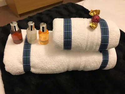 a pile of towels on a bed with bottles of alcohol at Castle Gait, Paisley in Paisley