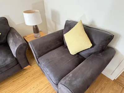 a black leather couch with a yellow pillow on it at Castle Gait, Paisley in Paisley