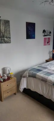 a bedroom with a bed and a wooden night stand at Homely Haven, Dunfermline in Dunfermline
