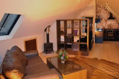 a living room with a leather couch and a wood stove at Finlaystone Barns in Port Glasgow