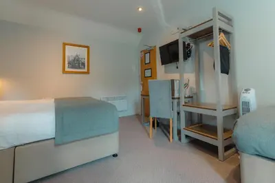 a bedroom with a bed and a desk and a bed and a room with at West Port Hotel in Linlithgow