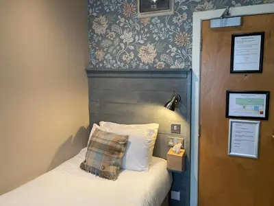 a bedroom with a bed with a wooden headboard at West Port Hotel in Linlithgow