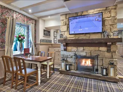 a living room with a table and a fireplace at West Port Hotel in Linlithgow