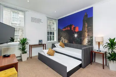 a living room with two beds and a large window at Stewart by Heeton Concept - Aparthotel Edinburgh in Edinburgh