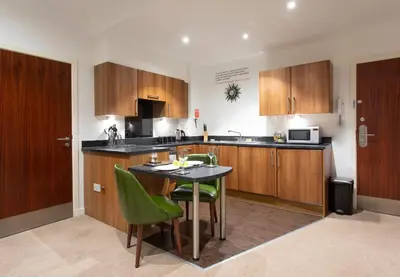 a kitchen with a table and green chairs in it at Stewart by Heeton Concept - Aparthotel Edinburgh in Edinburgh