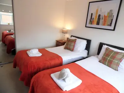 two beds in a room with red and white sheets at Signature - Brambling House in Coatbridge
