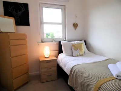 a bedroom with a bed and a dresser and a window at Signature - Brambling House in Coatbridge