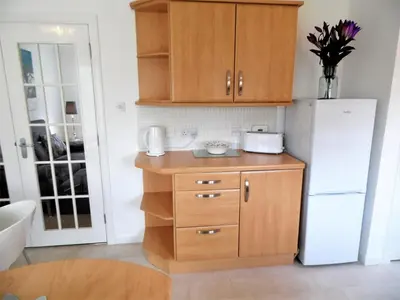 a kitchen with wooden cabinets and a white refrigerator at Signature - Brambling House in Coatbridge