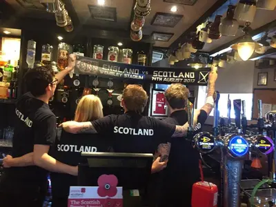 a group of people standing in a bar at The Blackbull Inn Polmont in Polmont