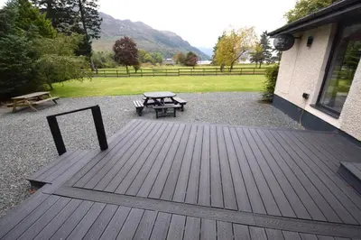 a wooden deck with a picnic table and a bench at Crann Mhor Holiday Home in Lochgoilhead
