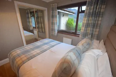 a bedroom with a large bed with a window at Crann Mhor Holiday Home in Lochgoilhead