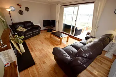 a living room with a leather couch and a television at Cobbler View No. 1 in Lochgoilhead