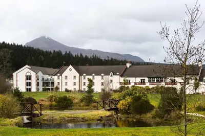 a large hotel with a mountain in the background at Auchrannie Resort in Brodick