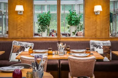 a restaurant with wooden tables and chairs and windows at Auchrannie Resort in Brodick