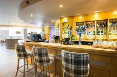 a bar with four chairs at a bar with liquor bottles at Auchrannie Resort in Brodick