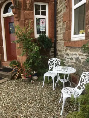 two chairs and a table in front of a building at Dunivaig B&B in Tarbert