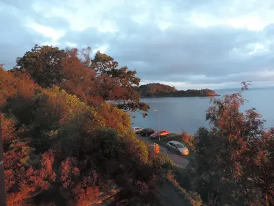two cars parked in a parking lot next to a lake at Dunivaig B&B in Tarbert