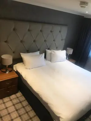 a large bed with white sheets and pillows at The Scot in Oban