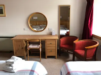 a room with two beds and a desk and a mirror at Port Askaig Hotel in Port Askaig