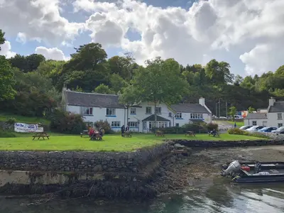 a white house next to a body of water at Port Askaig Hotel in Port Askaig