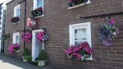 a brick building with lots of flowers in window boxes at Comelybank Guesthouse in Crieff