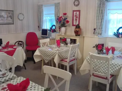a dining room with white tables and red chairs at Comelybank Guesthouse in Crieff