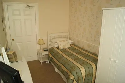a small bedroom with a bed and a door at Comelybank Guesthouse in Crieff