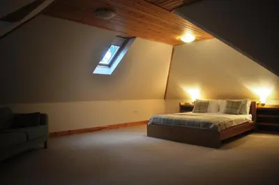 a bedroom with a bed and a window and a couch at The Old Coach House, Alltshellach Cottages in North Ballachulish