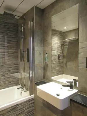 a bathroom with a sink and a tub and a mirror at The Craigie Hotel in Penicuik
