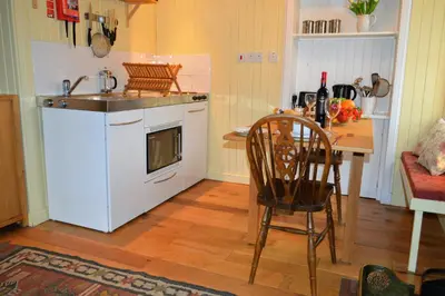 a kitchen with a sink and a stove and a table at Glenbranter Cottage in Strachur