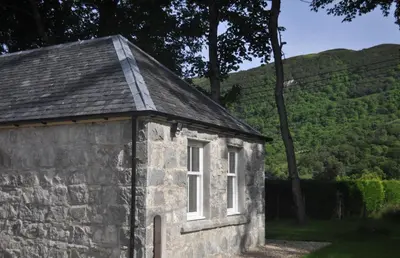 an old stone building with a window on the side at The Old Stables, Alltshellach Cottages in North Ballachulish
