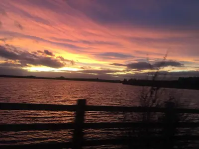 a sunset over a body of water with a fence at Bumble’s Barn in Slamannan