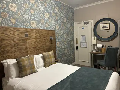 a bedroom with a bed and a desk and a mirror at The Abbey Inn in Paisley