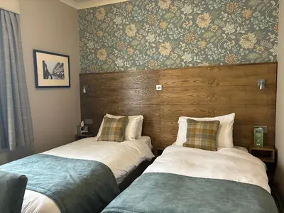 two beds sitting next to each other in a room at The Abbey Inn in Paisley
