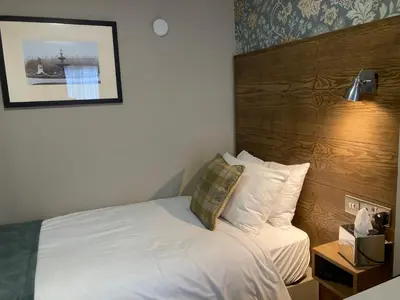a bedroom with a white bed with a wooden headboard at The Abbey Inn in Paisley