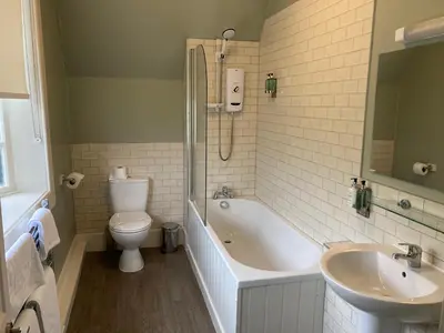 a bathroom with a tub and a toilet and a sink at Tullie Inn in Balloch