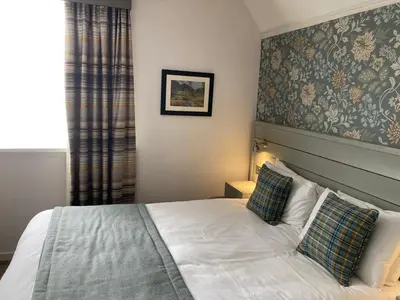 a bedroom with a white bed with two pillows at Tullie Inn in Balloch