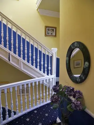 a staircase with a mirror and a vase with purple flowers at Ardleigh House in Edinburgh