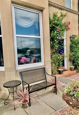 a bench and a table in front of a window at Ardleigh House in Edinburgh