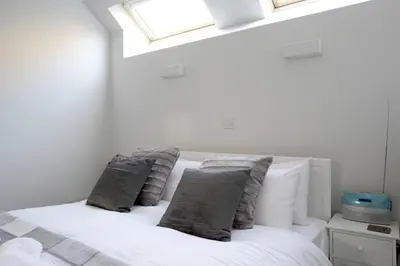 a bedroom with a white bed with pillows and a window at Quiet Ground Floor Mews Flat and parking in Edinburgh